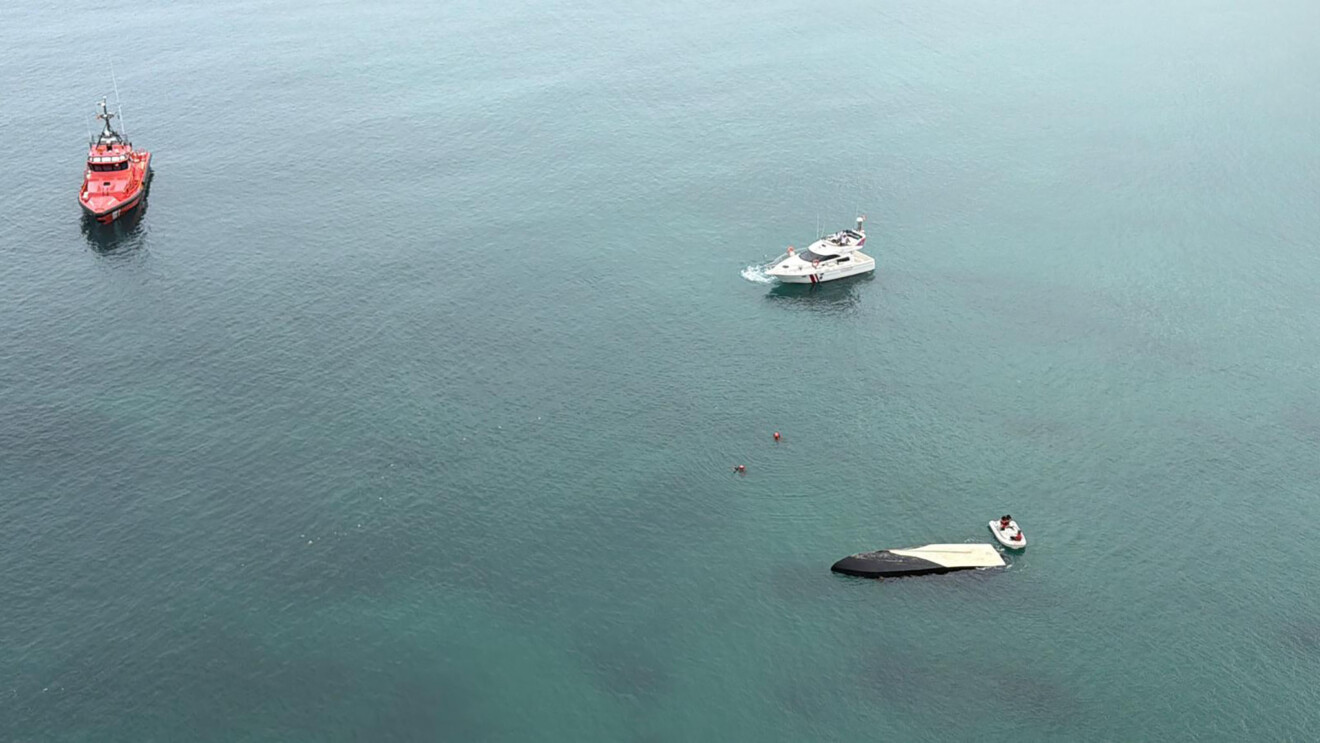 Velero eléctrico volcado y semihundido en el puerto de Dénia durante el operativo de emergencia