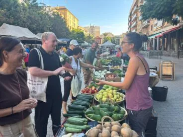 Dénia, referente europeo: un experto alemán estudia sus mercados y gastronomía 3 El técnico Daniel Schellwald hablando con una vendedora en un puesto de verduras del mercado al aire libre de Dénia.