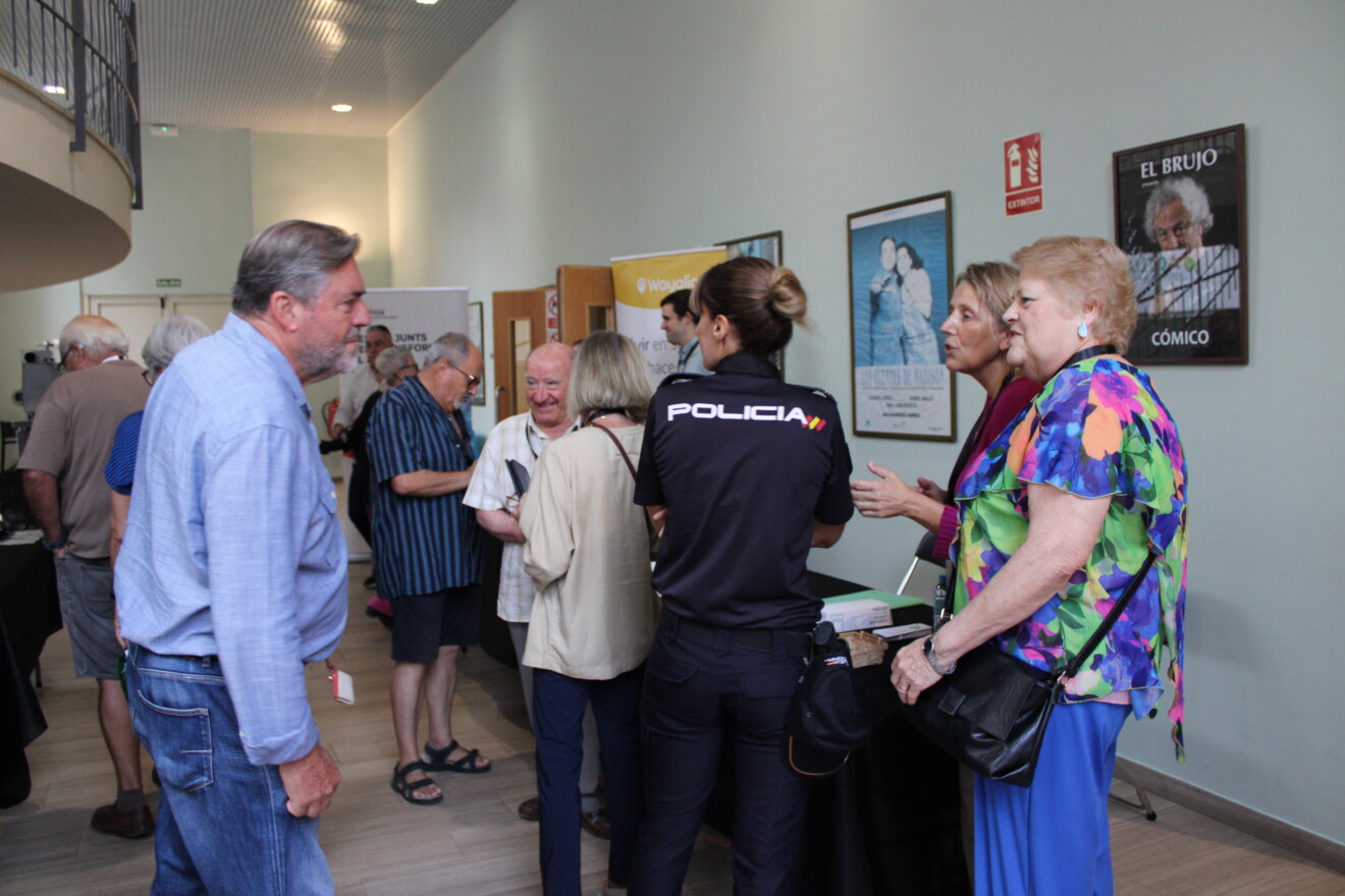 Asistentes conversan junto a los estands instalados en el Centro Social de Dénia como actividad complementaria a la jornada dedicada a las personas mayores