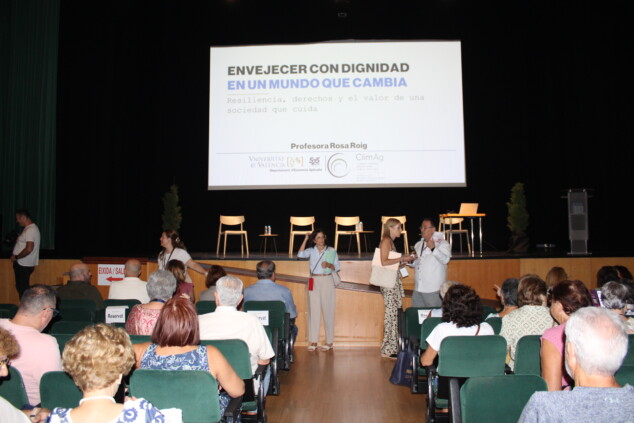 Dénia reivindica a sus mayores: una jornada sobre derechos, cuidados y longevidad 1 Imagen: Público reunido en el auditorio del Centro Social de Dénia ante una pantalla que anuncia una ponencia de Rosa Roig sobre envejecer con dignidad.