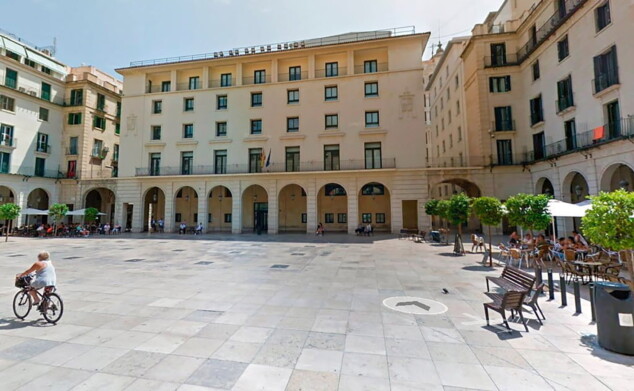 Más de dos años acusados de lesionar a su bebé: la Justicia absuelve a una pareja de Dénia 1 Imagen: Plaza peatonal con un edificio de fachada clara y soportales, terrazas y árboles.