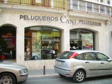 Fachada de Cani Peluqueros en Dénia, con varios coches estacionados frente al establecimiento antes de la peatonalización de la calle.