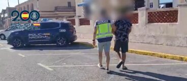 Detenido en Dénia un varón por una serie de robos en mezquitas de Alicante, Elx y Gandia 2 Un agente de la Policía Nacional escolta a un hombre detenido y esposado en un aparcamiento exterior.