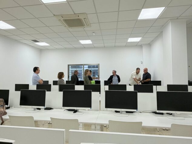 La DGT prueba la nueva aula de exámenes teóricos informatizados en Dénia 1 Imagen: Varios representantes de la DGT y el Ayuntamiento de Dénia inspeccionan una sala con filas de ordenadores para exámenes.